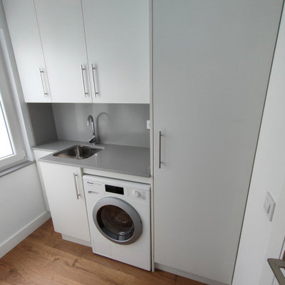 Dedicated laundry room - mid-sized transitional single-wall medium tone wood floor and brown floor dedicated laundry room idea in Other with an undermount sink, flat-panel cabinets, white cabinets, quartz countertops, white walls, an integrated washer/dryer and gray countertops