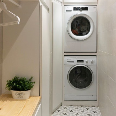 Example of a small eclectic l-shaped ceramic tile and gray floor utility room design in Madrid with open cabinets, white cabinets, wood countertops, white walls, a stacked washer/dryer and brown countertops