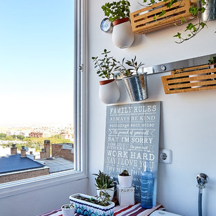 Cette photo montre une petit buanderie linéaire multi-usage avec un placard à porte plane, des portes de placard blanches, un plan de travail en stratifié, un mur blanc, un sol en carrelage de porcelaine, un sol gris et un plan de travail rouge.