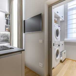 Ispirazione per una piccola sala lavanderia design con lavello da incasso, ante lisce, ante bianche, top in laminato, pareti grigie, pavimento in gres porcellanato, lavatrice e asciugatrice a colonna e top bianco