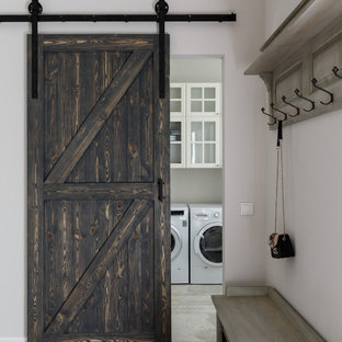Idee per una grande sala lavanderia country con lavatoio, ante di vetro, ante bianche, pareti grigie, pavimento in gres porcellanato, lavatrice e asciugatrice affiancate e pavimento grigio