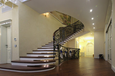 На фото: большая изогнутая бетонная лестница в классическом стиле с деревянными ступенями