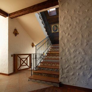 Foto di una scala a "U" country con pedata in legno, alzata piastrellata e parapetto in metallo