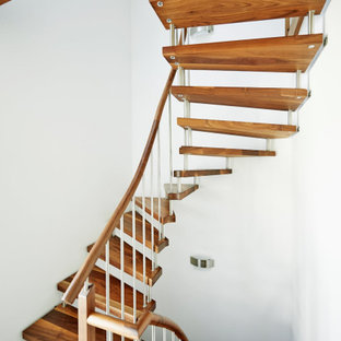 Ispirazione per una scala curva scandinava con pedata in legno e parapetto in legno
