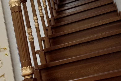 На фото: большая угловая деревянная лестница с деревянными ступенями и деревянными перилами