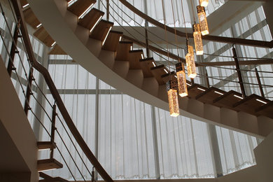 На фото: большая изогнутая деревянная лестница с деревянными ступенями и деревянными перилами
