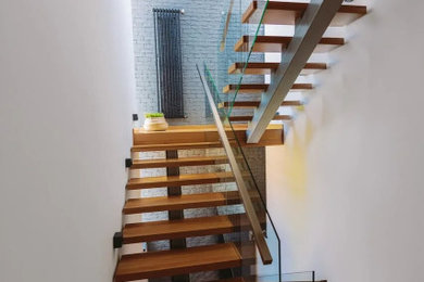 Exemple d'un escalier tendance en U de taille moyenne avec des marches en bois et un garde-corps en verre.