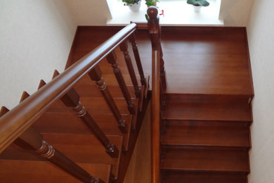 На фото: большая п-образная деревянная лестница с деревянными ступенями и деревянными перилами с