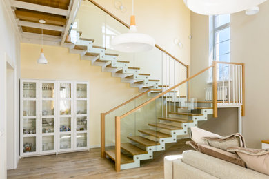 Идея дизайна: большая п-образная лестница с деревянными ступенями и стеклянными перилами без подступенок