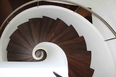 На фото: винтовая деревянная лестница среднего размера в современном стиле с деревянными ступенями и металлическими перилами с