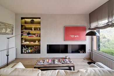 Example of a mid-sized trendy formal and enclosed medium tone wood floor living room design in Barcelona with beige walls, a standard fireplace and no tv