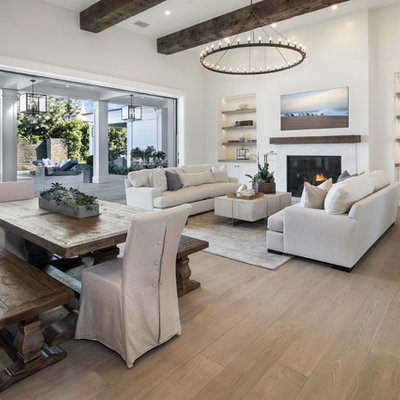 Example of a transitional open concept medium tone wood floor and brown floor living room design in Orange County with white walls and a standard fireplace