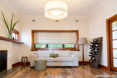 Exemple d'un salon tendance avec une salle de réception, un mur beige, un sol en bois brun, une cheminée standard et un manteau de cheminée en brique.