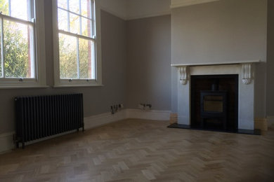 Ejemplo de salón contemporáneo de tamaño medio con suelo de madera en tonos medios, estufa de leña y marco de chimenea de piedra