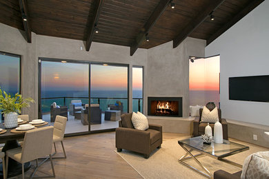 Example of a large trendy open concept light wood floor living room design in Orange County with gray walls, a standard fireplace, a concrete fireplace and a wall-mounted tv