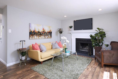 ワシントンD.C.にあるエクレクティックスタイルのおしゃれなLDK (グレーの壁、濃色無垢フローリング、標準型暖炉、漆喰の暖炉まわり、壁掛け型テレビ、茶色い床) の写真