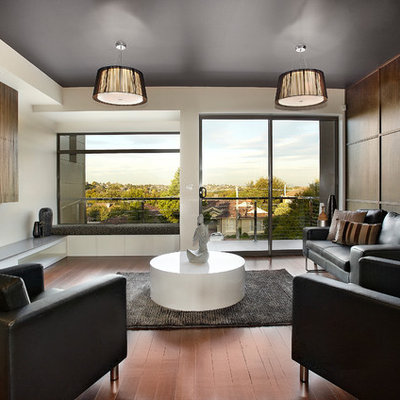 Mid-sized trendy enclosed medium tone wood floor living room photo in Melbourne with white walls and no fireplace
