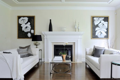 This is an example of a classic living room in Montreal with beige walls, a standard fireplace and a wooden fireplace surround.