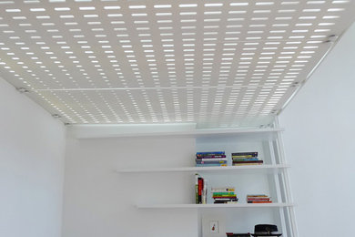 Idéer för små funkis loftrum, med ett bibliotek, vita väggar, ljust trägolv, en väggmonterad TV och beiget golv