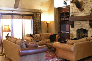 Modelo de salón para visitas abierto rústico de tamaño medio sin televisor con paredes beige, suelo de madera en tonos medios, chimeneas suspendidas, marco de chimenea de piedra y suelo marrón