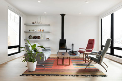 Imagen de salón abierto contemporáneo de tamaño medio sin televisor con paredes blancas, suelo de madera clara, suelo marrón y estufa de leña