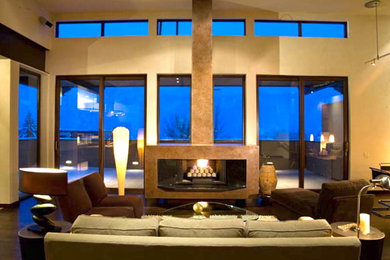 Diseño de salón moderno con paredes beige, suelo de madera oscura, todas las chimeneas y marco de chimenea de metal