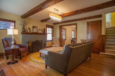 Réalisation d'un salon chalet de taille moyenne avec un mur beige, parquet clair, une cheminée standard, un manteau de cheminée en brique et un sol marron.