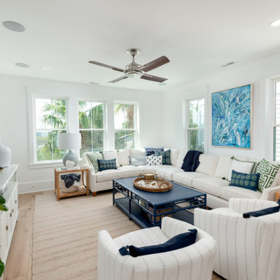 Inspiration for a mid-sized tropical open concept medium tone wood floor and brown floor living room remodel in Charleston with white walls, a wall-mounted tv and no fireplace
