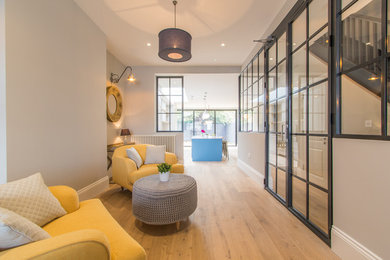 Foto de salón contemporáneo de tamaño medio con paredes grises, suelo de madera clara y suelo beige