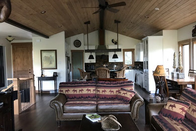 Example of a mid-sized mountain style formal and open concept dark wood floor and brown floor living room design in Denver with beige walls, a standard fireplace, a stone fireplace and a tv stand