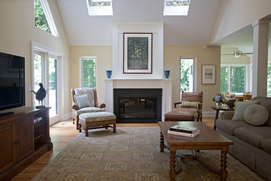 Example of a mid-sized transitional open concept light wood floor and brown floor living room design in New York with beige walls, a standard fireplace, a wood fireplace surround and a tv stand