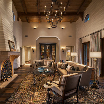 A great room with soaring ceilings, wood beams and corbels, and adobe brick wall