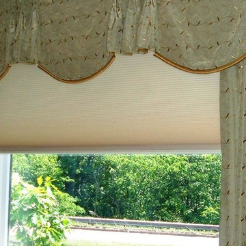 A large cellular shade under a drapery