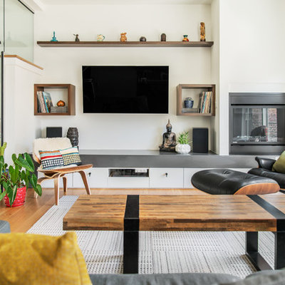 Inspiration for a mid-sized contemporary open concept medium tone wood floor and brown floor living room remodel in Seattle with white walls, a standard fireplace, a metal fireplace and a wall-mounted tv