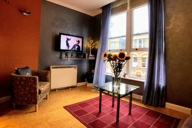 Modelo de salón para visitas cerrado clásico pequeño con paredes multicolor, suelo vinílico, televisor colgado en la pared y suelo naranja