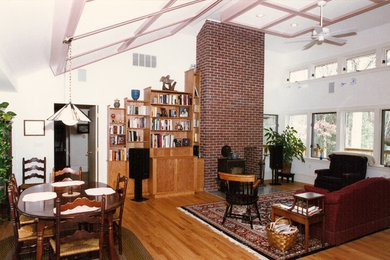 Mittelgroßes, Offenes Modernes Wohnzimmer mit weißer Wandfarbe, braunem Holzboden, Kaminofen, Kaminumrandung aus Backstein und braunem Boden in Boston