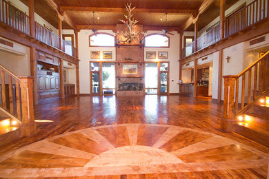 Modelo de salón abierto de estilo americano grande con paredes blancas y suelo de madera en tonos medios