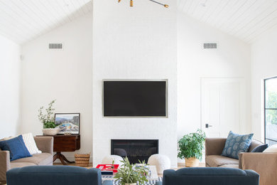 ロサンゼルスにあるラグジュアリーな広いトランジショナルスタイルのおしゃれなリビング (白い壁、無垢フローリング、標準型暖炉、レンガの暖炉まわり、壁掛け型テレビ、茶色い床) の写真