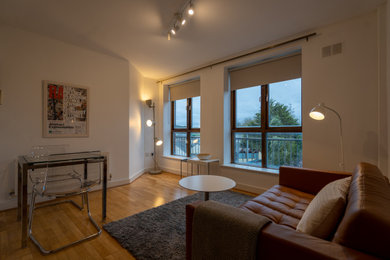Diseño de salón cerrado minimalista de tamaño medio con paredes blancas, suelo de madera clara y suelo marrón