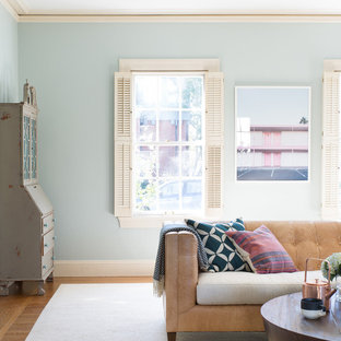 Inspiration for an eclectic medium tone wood floor living room remodel in San Francisco with blue walls, a standard fireplace and a wood fireplace surround