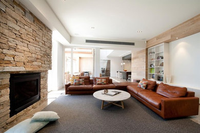 Modelo de salón abierto minimalista de tamaño medio con paredes blancas, suelo de cemento, todas las chimeneas, marco de chimenea de piedra y televisor colgado en la pared