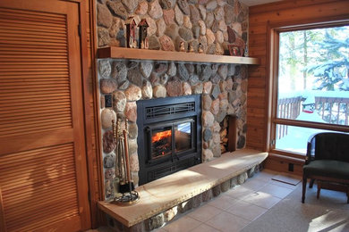 Example of a mid-sized mountain style formal and enclosed ceramic tile living room design in Other with multicolored walls, a standard fireplace, a stone fireplace and no tv