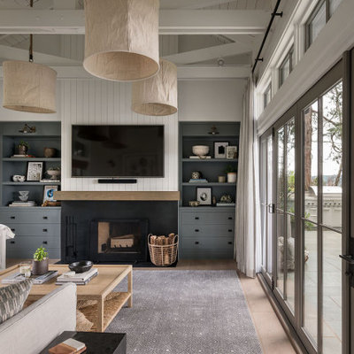 Living room - cottage light wood floor, brown floor and shiplap wall living room idea in Seattle with white walls, a standard fireplace, a wall-mounted tv and a metal fireplace
