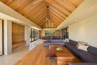 Living room - tropical open concept medium tone wood floor living room idea in Hawaii with gray walls and a media wall