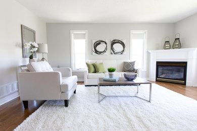Пример оригинального дизайна: гостиная комната в современном стиле с серыми стенами, паркетным полом среднего тона, угловым камином, фасадом камина из дерева и коричневым полом