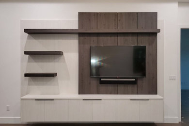 Modelo de salón abierto minimalista grande sin chimenea con paredes blancas, suelo de madera en tonos medios, televisor colgado en la pared y suelo marrón