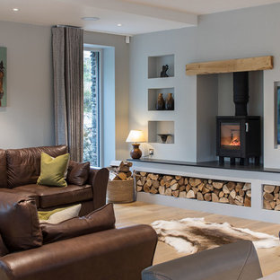 Inspiration for a classic living room in Other with grey walls, light hardwood flooring, a wood burning stove, a wall mounted tv and beige floors.