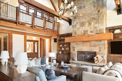 Inspiration for a large rustic formal and enclosed dark wood floor and brown floor living room remodel in Other with beige walls, a standard fireplace, a stone fireplace and a media wall