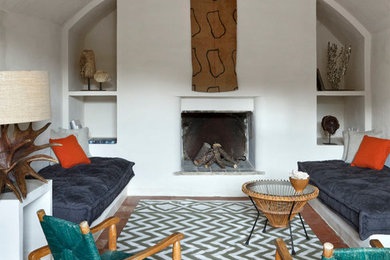 他の地域にあるエクレクティックスタイルのおしゃれな応接間 (白い壁、テラコッタタイルの床、標準型暖炉、漆喰の暖炉まわり) の写真