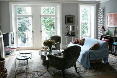 Пример оригинального дизайна: парадная гостиная комната в классическом стиле с серыми стенами, паркетным полом среднего тона и отдельно стоящим телевизором